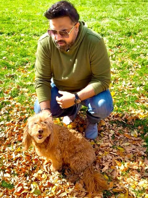 Mo kneeling beside a dog in autumn leaves